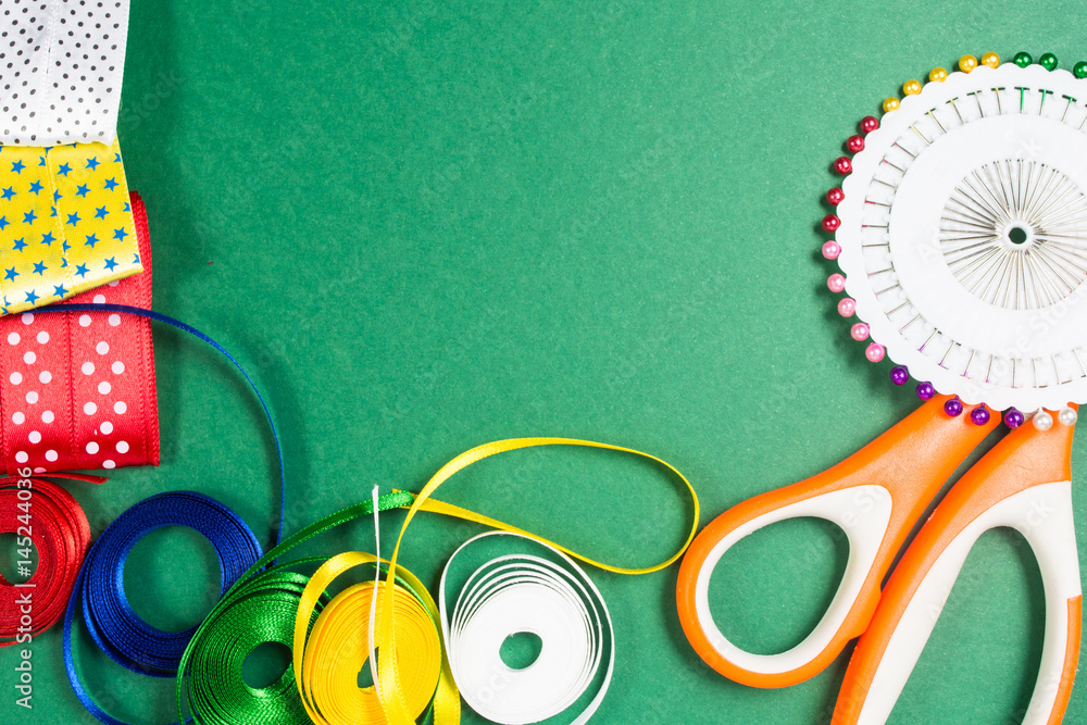 Fototapeta premium Scissors, pins and color tapes on green background