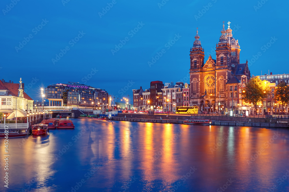 Night city view of Amsterdam canal, bridge and Basilica of Saint Nicholas, Holland, Netherlands. Long exposure