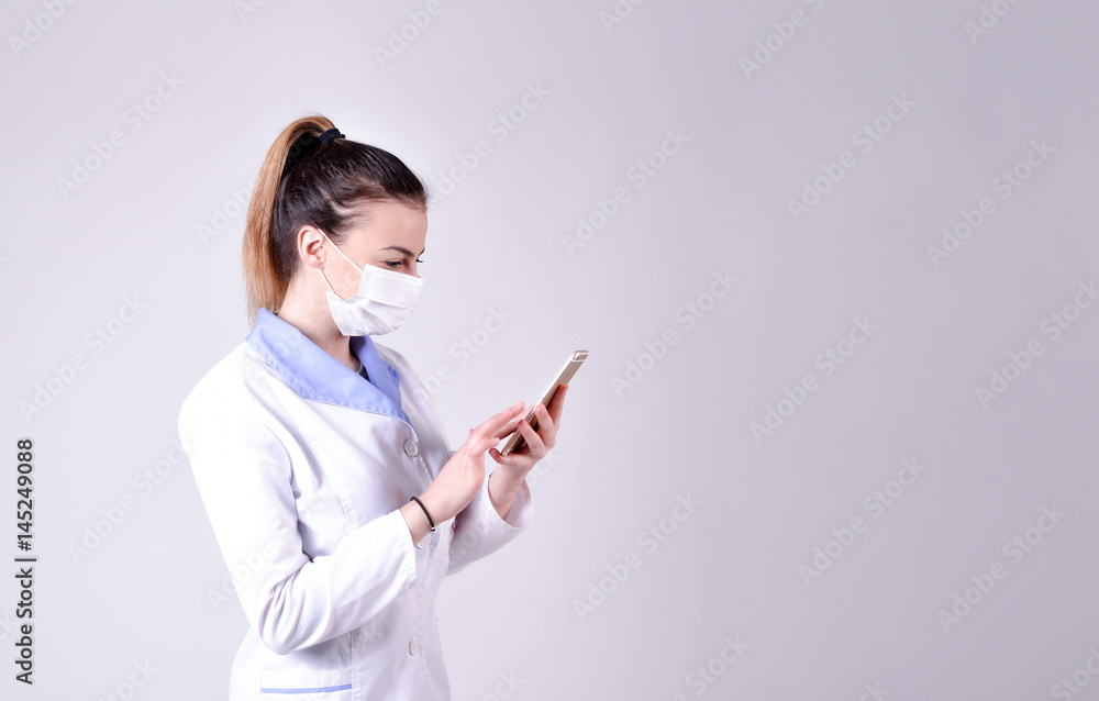 Young nurse in a protective mask typing on smartphone Young nurse in a protective mask typing on smartphone