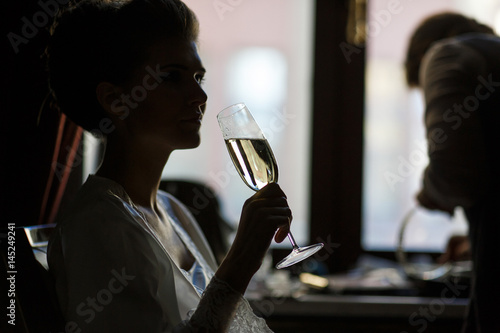 Bride drinks champagne sitting in silk robe