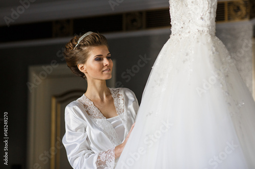 Dreamy bride admires her rich wedding dress