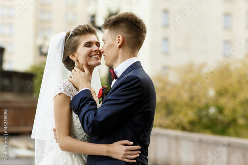 Groom touches bride's neck tender before a kiss