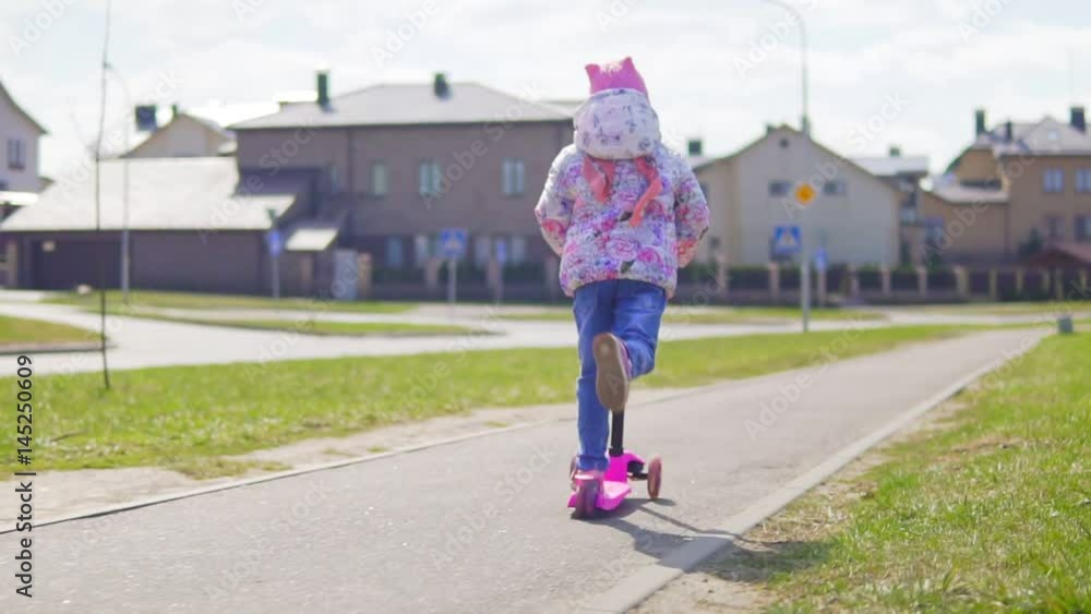 A child is riding a scooter on a sunny day. Slow motion A child is riding a scooter on a sunny day. Slow motion