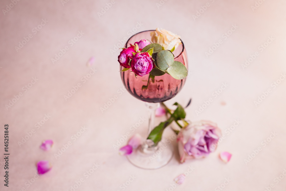 Violet hydrangea lies beneath glass with pink rose buds