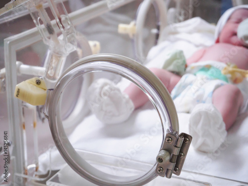 Newborn baby girl inside incubator in hospital post delivery room