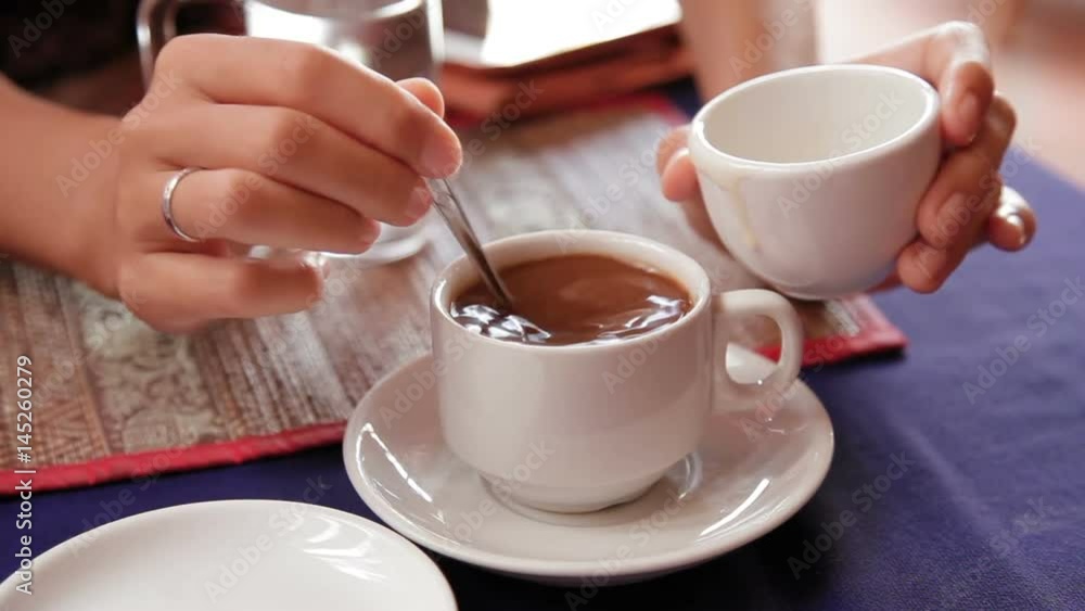Woman adding coconut condensed milk in strong black coffee. Asian cuisine, traditional Asian method of brewing coffee. Cambodia. Woman adding coconut condensed milk in strong black coffee. Asian cuisine, traditional Asian method of brewing coffee. Cambodia.