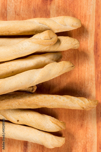 Pile of saulty grissini sticks in flat lay image on the wooden planks board photo