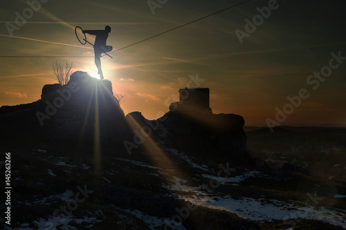 Człowiek na linie na zamku w Olsztynie o zachodzie słońca.