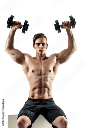 Sporty man in training pumping up muscles of the back and hands with dumbbells. Photo of strong male with naked torso isolated on white background. Strength and motivation. photo