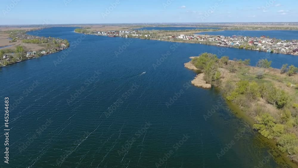 Splendid view on the beautiful blue waters of the Dnipro with its two river banks and a lot of wild greenary on them, in the early spring in a sunny daytime, being shot from an aerial perspective Splendid view on the beautiful blue waters of the Dnipro with its two river banks and a lot of wild greenary on them, in the early spring in a sunny daytime, being shot from an aerial perspective