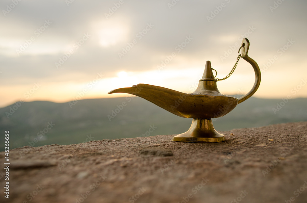 Antique artisanal Aladdin Arabian nights genie style oil lamp with soft  light white smoke. Sunset mountain background Stock-Foto | Adobe Stock