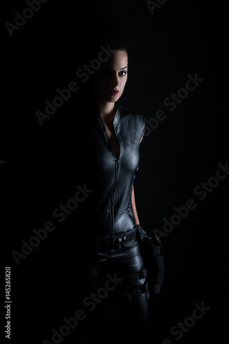 Superhero police woman in a leather catsuit with guns