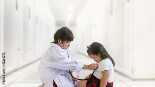Asian child in doctor suit examining her baby