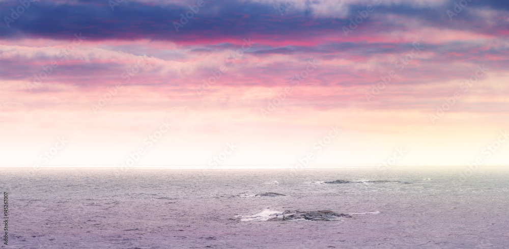 Obraz premium Partly cloudy panorama in vivid colors at seashore with small islets in the sea
