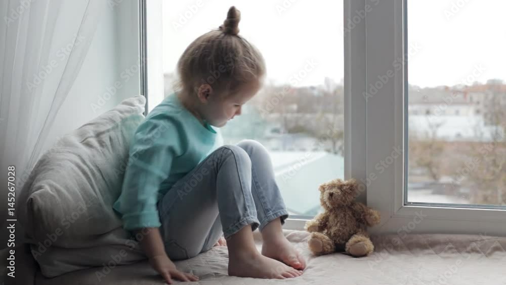 Sad girl sitting on windowsill Sad girl sitting on windowsill