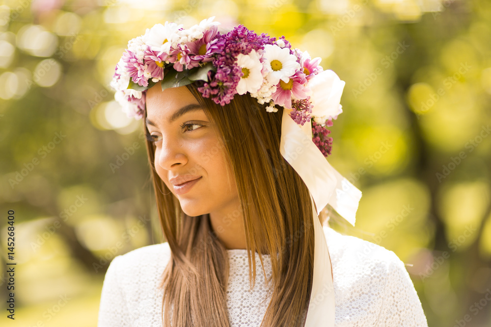 Obraz premium Young woman with flowers in her hair on sunny spring day