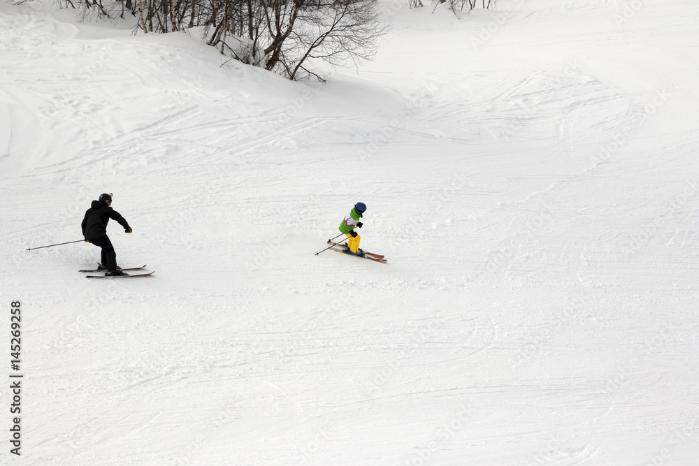 Skiers on ski slope at winter day