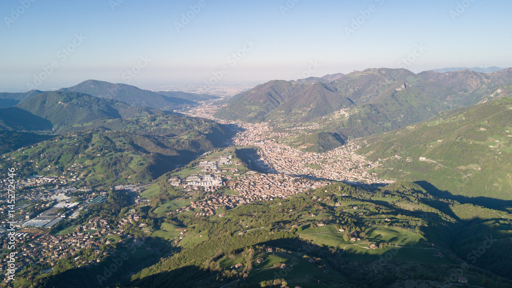 4K Drone aerial view to the Seriana valley and Orobie Alps in a clear and blue day. View of the highest mountains including Arera. Panorama from Farno Mountain, Bergamo, Italy. 