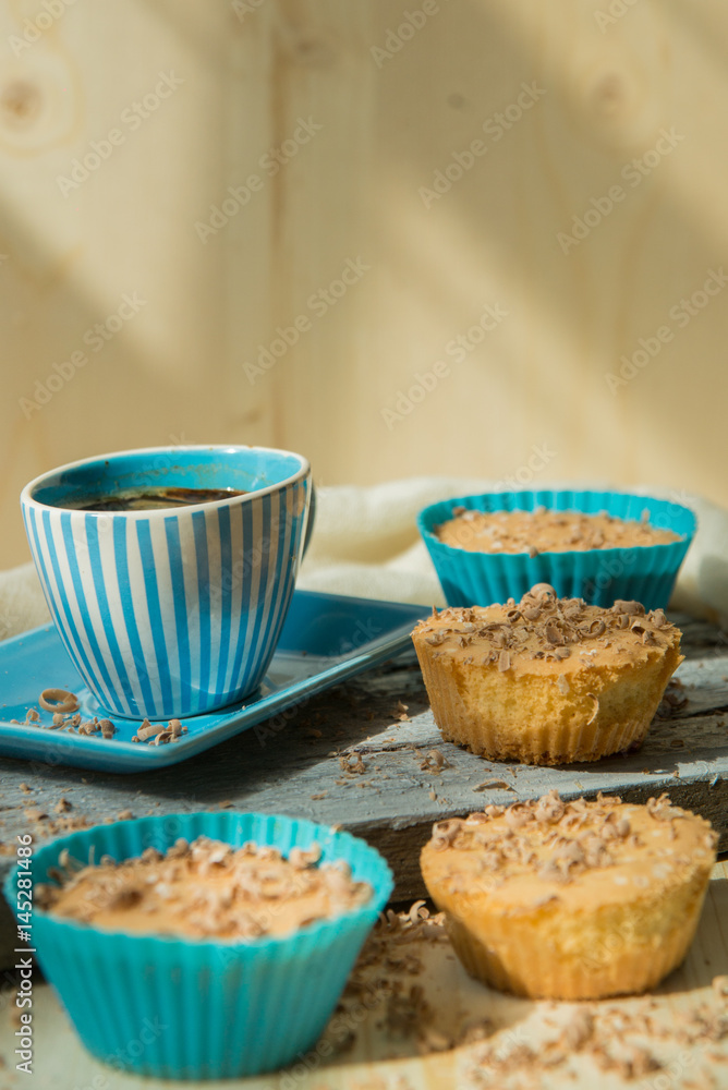 Chocolate muffin with soft cream and fresh blueberry powdered with sugar, cup of coffee, rustic background Chocolate muffin with soft cream and fresh blueberry powdered with sugar, cup of coffee, rustic background