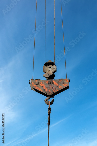 Hook of a construction crane on a wire blue background with a blue sky