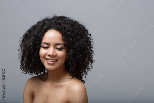 Close-up studio portrait of a beautiful young woman smiling and looking down