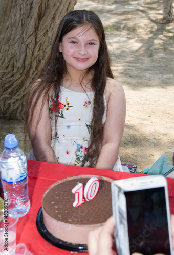beautiful girl chocolate cake on red tablecloth with candles 10 birthday somebody take a foto with cellular phone