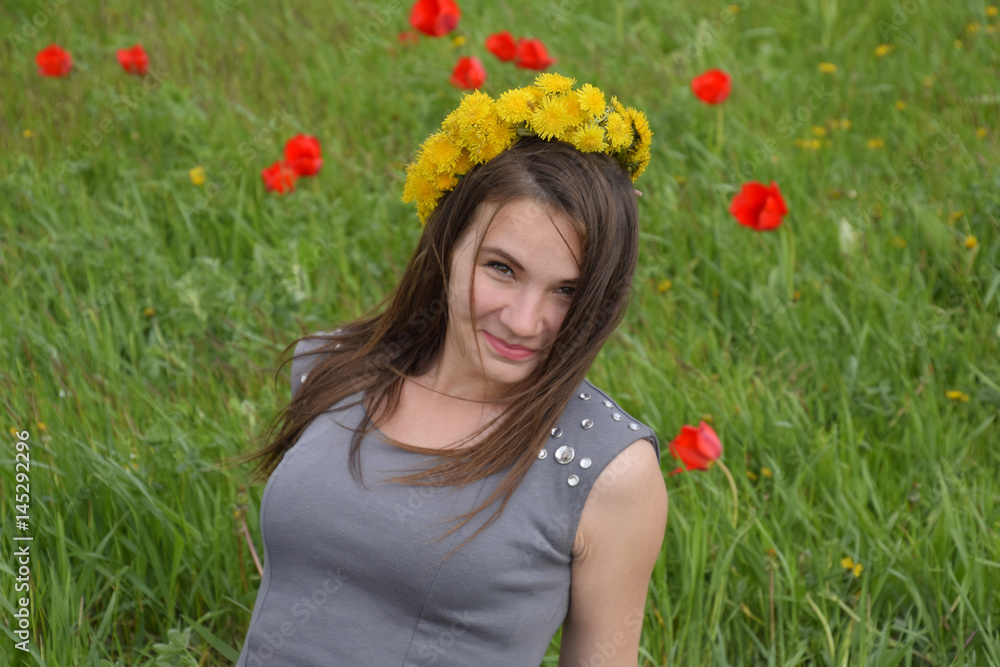 A girl with a wreath of dandelions on her head. Beautiful fairy young girl in a field among the flowers of tulips. A girl with a wreath of dandelions on her head. Beautiful fairy young girl in a field among the flowers of tulips.