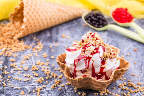 An ice cream basket with raspberry jam, sprinkled shredded nuts photo