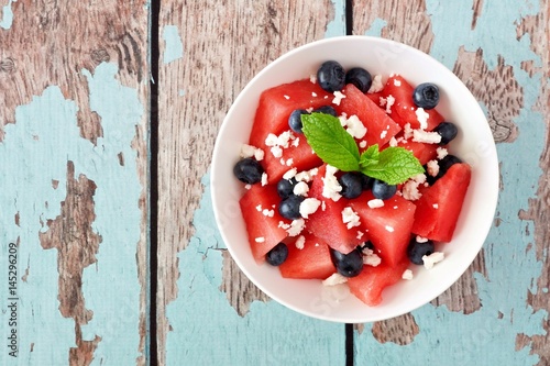 Summer salad with watermelon, blueberries and feta cheese, above view on a rustic blue wood background