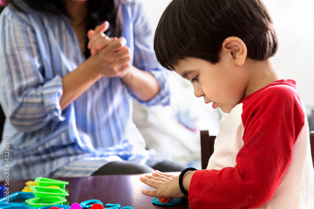 Boy playing with toy while mother sitting in background Boy playing with toy while mother sitting in background