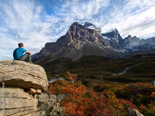 Fotografie Young man sitting and enjoying scenic view at a high mountain