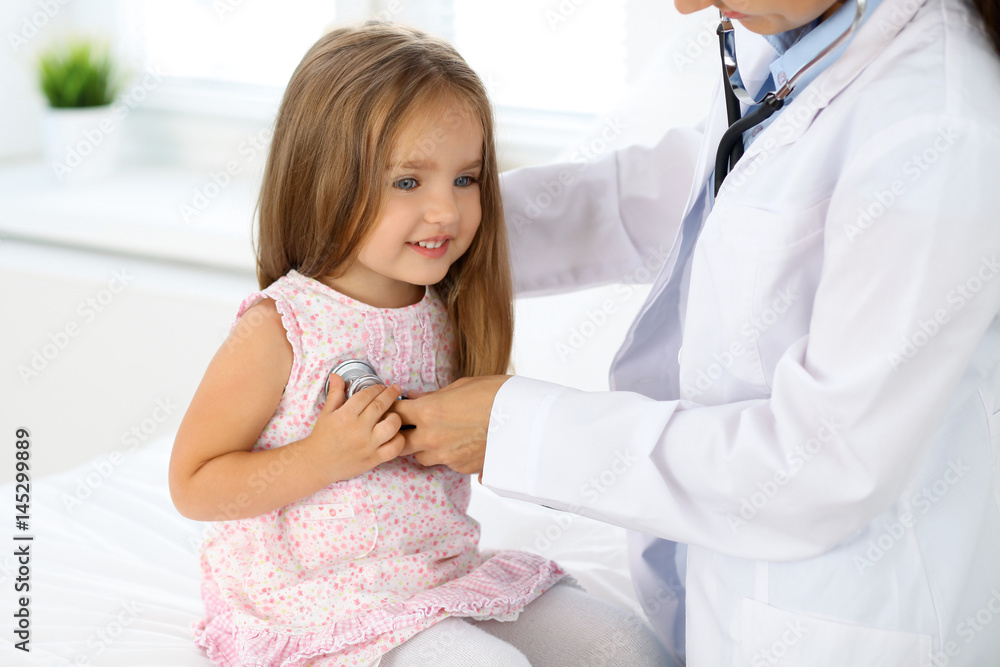 Fototapeta premium Doctor examining a little girl by stethoscope