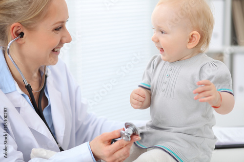 Pediatrician is taking care of baby in hospital. Little girl is being examine by doctor with stethoscope. Health care, insurance and help concept.