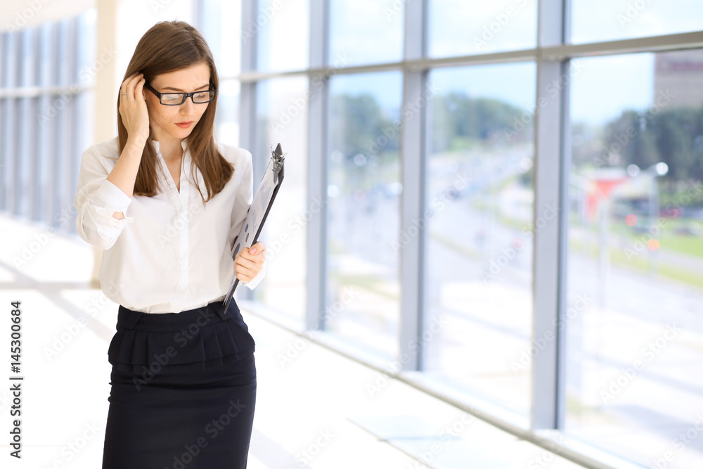 Modern business woman standing and keeping a clipboard in the office. Modern business woman standing and keeping a clipboard in the office.