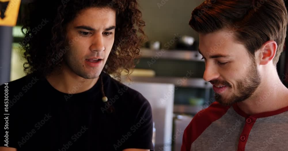Two men interacting with each other while using digital tablet Two men interacting with each other while using digital tablet