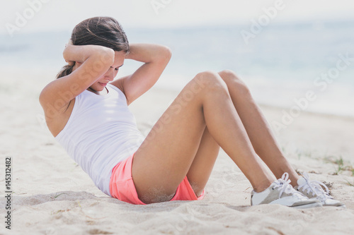 sporty woman doing sit up at the beach