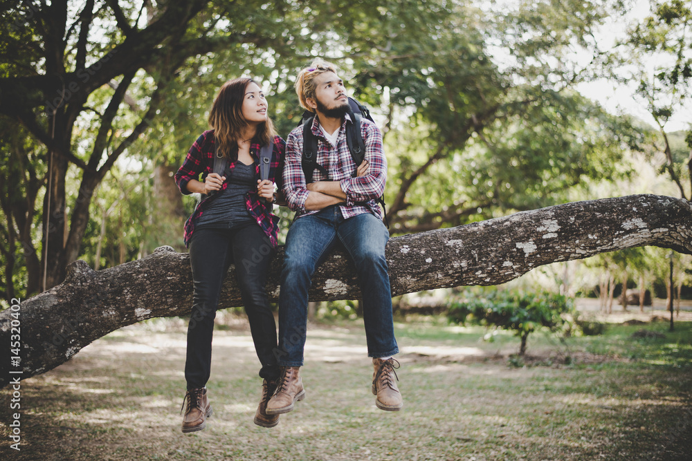 Young hikers couple take a rest sitting on branch enjoy with nature. Travel concept. Young hikers couple take a rest sitting on branch enjoy with nature. Travel concept.