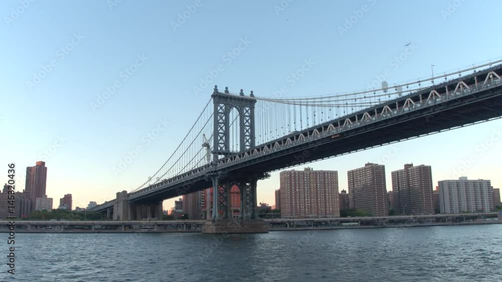 LOW ANGLE VIEW, CLOSE UP: Sightseeing cruise on East River along famous New York City skyline. Skyscrapers, office buildings and luxury waterfront condominiums along iconic Manhattan Bridge at sunrise LOW ANGLE VIEW, CLOSE UP: Sightseeing cruise on East River along famous New York City skyline. Skyscrapers, office buildings and luxury waterfront condominiums along iconic Manhattan Bridge at sunrise
