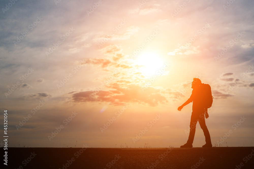 Silhouette of the young backpacker man walking during sunset. Silhouette of the young backpacker man walking during sunset.