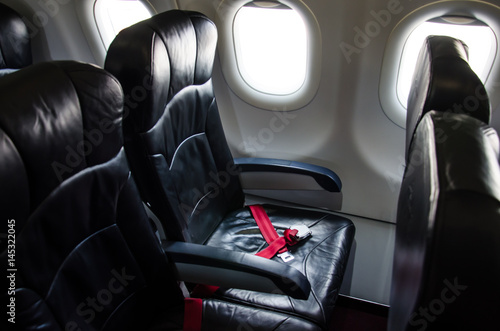 Seat belt on seat shot in airplane with Black seat.