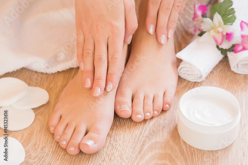 Young woman's hands applying a foot moisturizing cream. Pedicure beauty salon.