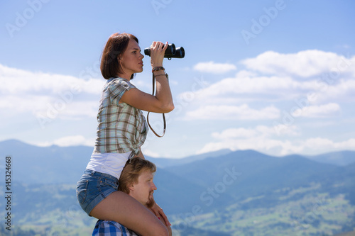 Young couple of travelers looking through binoculars