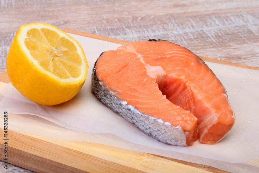 fresh raw salmon with spices and lemon on wooden cutting board. ready for cookin fresh raw salmon with spices and lemon on wooden cutting board. ready for cookin