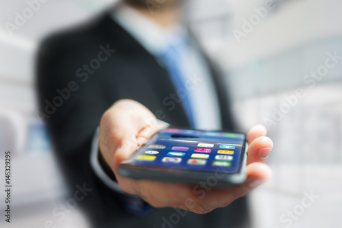 Hand of a business man holding black smartphone with operating system screen