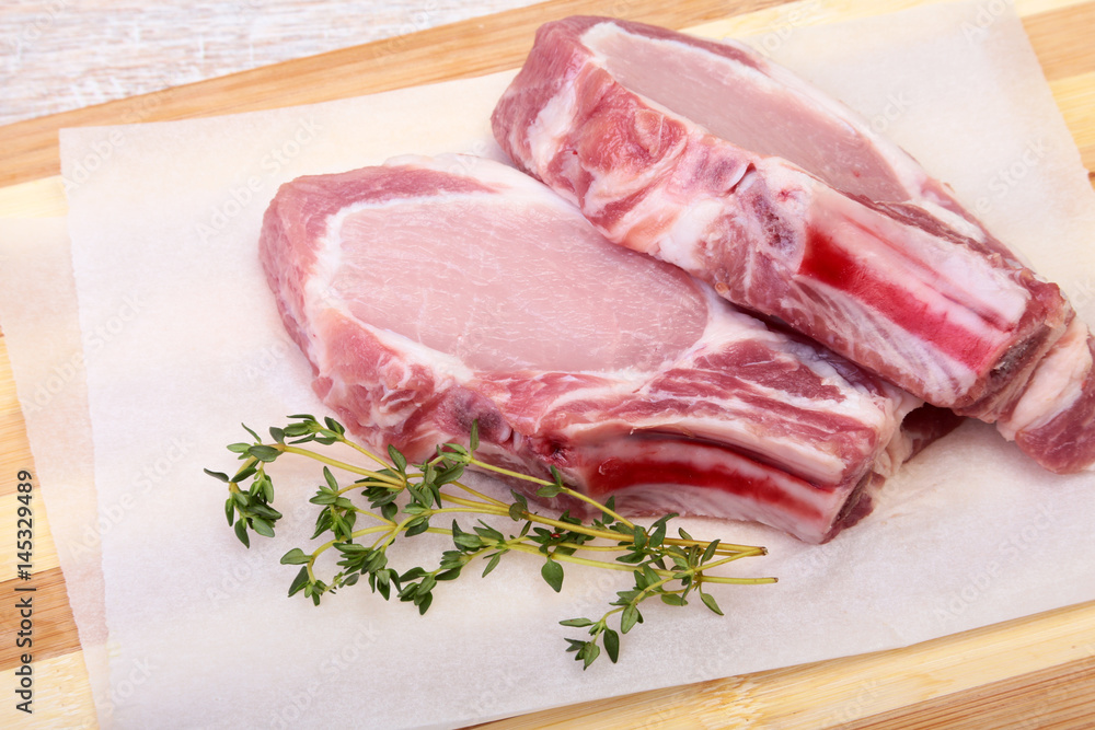 Raw pork chops, spices and rosemary on cutting board. Ready for cooking. Raw pork chops, spices and rosemary on cutting board. Ready for cooking.
