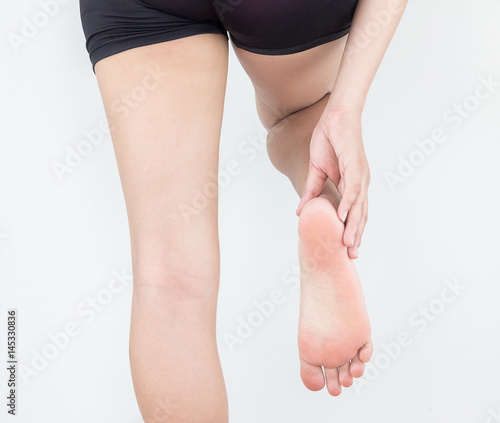 Heel pain in women, Woman massaging her foot.