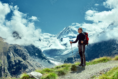 hiker at the top of a pass with backpack enjoy sunny day in Alps. Switzerland, Trek near Matterhorn mount.