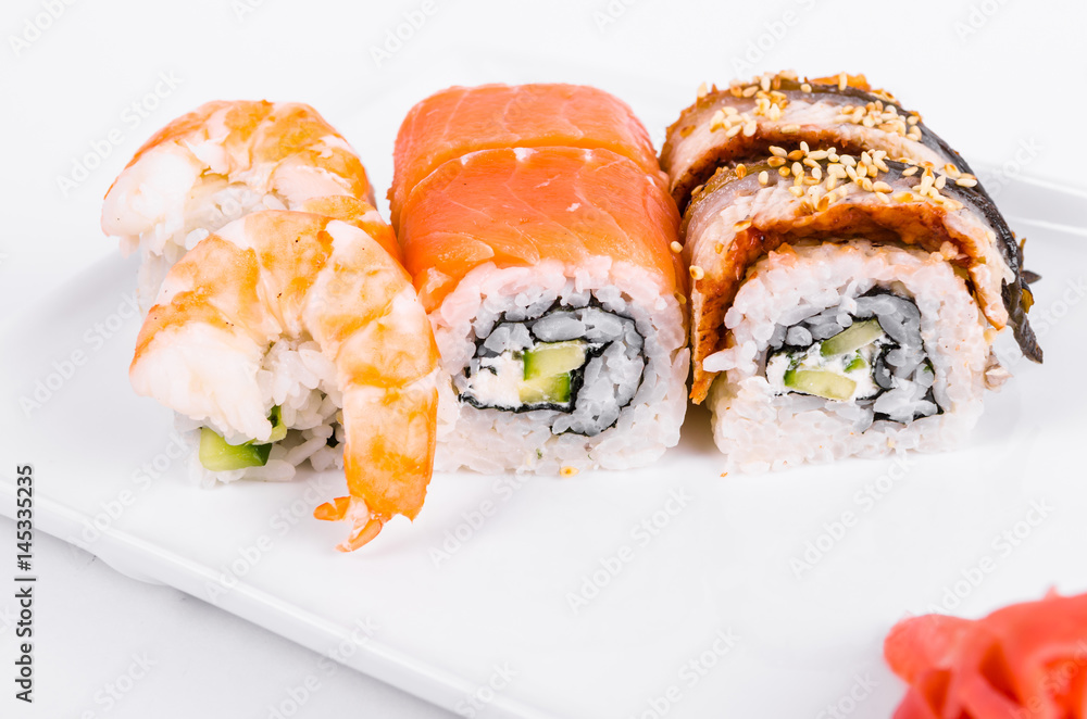 Asia. Tokyo rolls with shrimp, eel and salmon on a white plate on a white background Asia. Tokyo rolls with shrimp, eel and salmon on a white plate on a white background