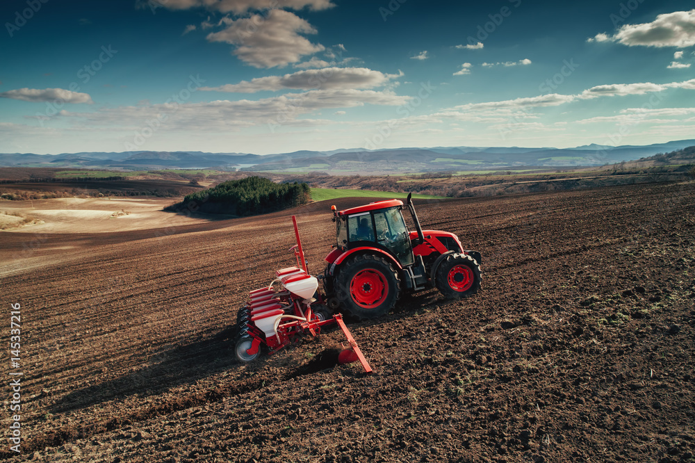 Fototapeta premium Aerial view of tractors working on the harvest field