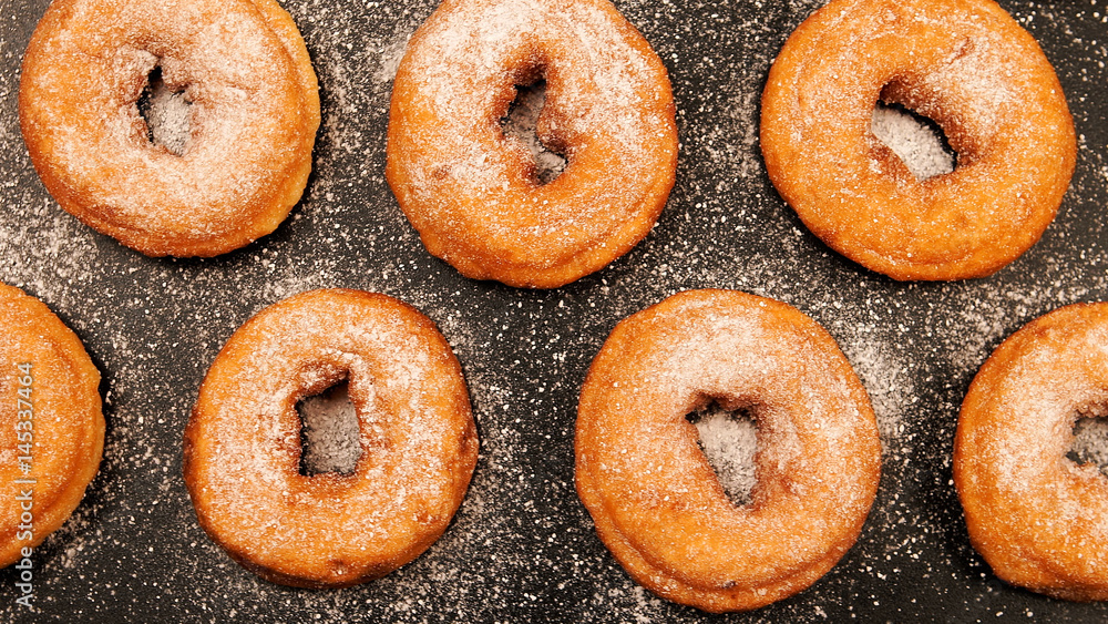 TOP VIEW: Doughnuts with sugar powder on the black desk